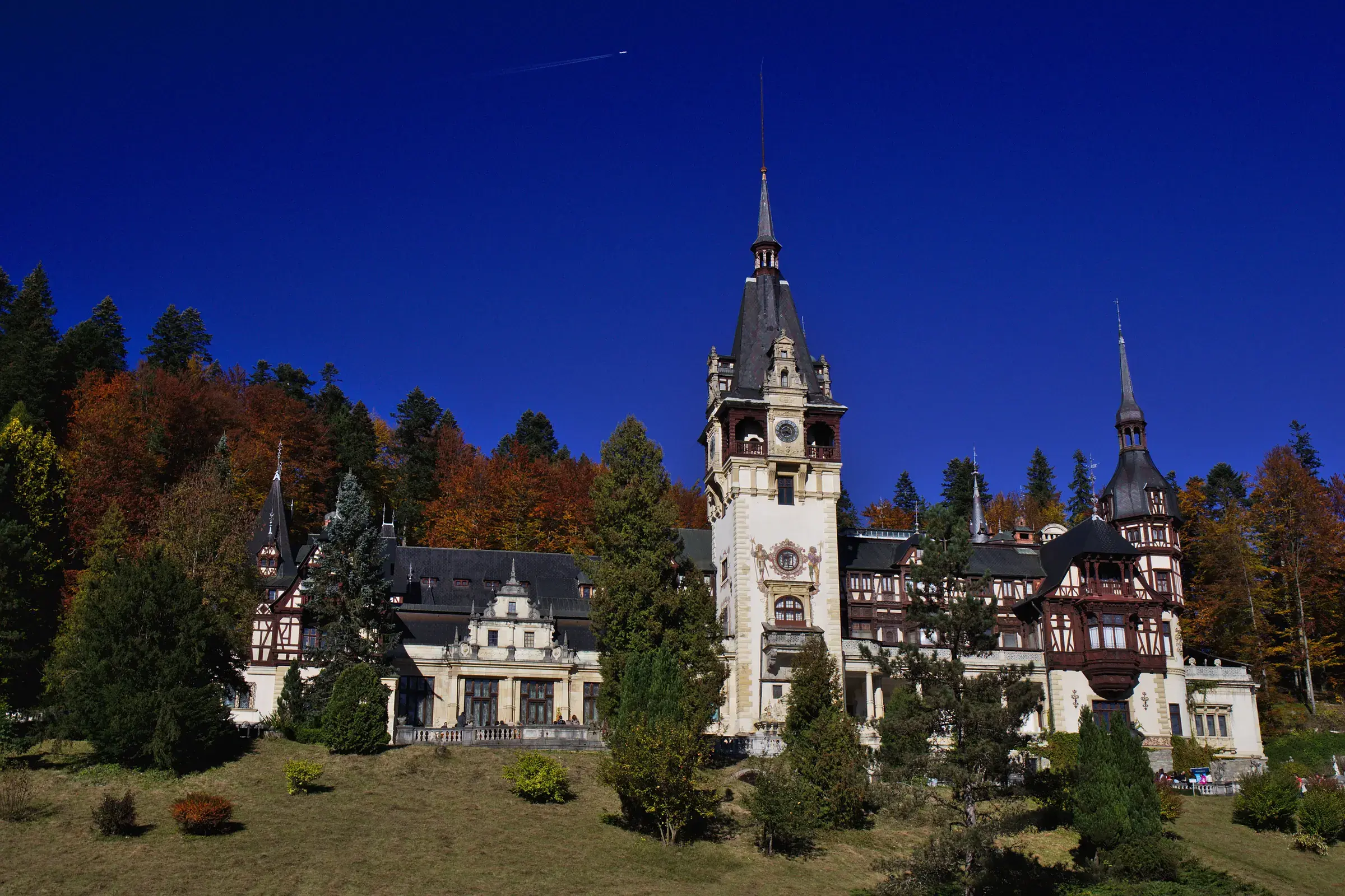 Peleș Castle with its clock tower under a dark blue sky
